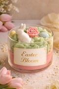 Artisan whipped three-wick candle in a clear glass jar labeled "Easter Bloom," featuring pastel pink and green whipped coconut soy wax with decorative floral embeds, scented in lilac lemonade for a fresh spring aroma. 
