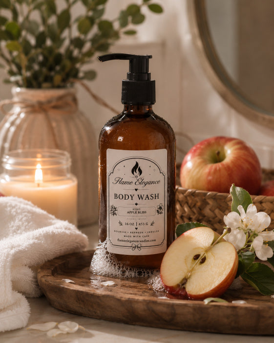 An amber glass pump bottle of Apple Bliss Body Wash by Flame Elegance  with an apple slice, white blossoms, a lit candle, and a towel in a warm, rustic bathroom setting.