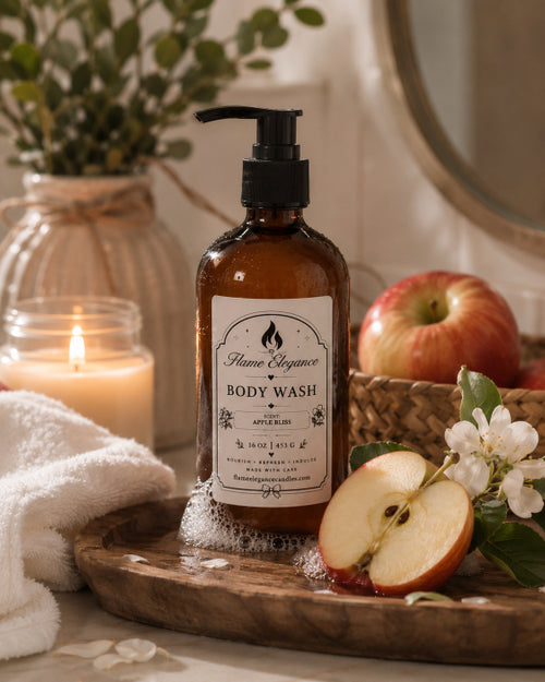 An amber glass pump bottle of Apple Bliss Body Wash by Flame Elegance  with an apple slice, white blossoms, a lit candle, and a towel in a warm, rustic bathroom setting.