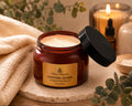 Jar of luxe whippedSapphire Desire whipped body butter with a black lid on a wooden surface, surrounded by eucalyptus leaves and a towel by Flame Elegance