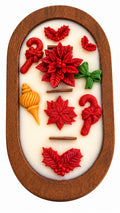An oval wood dough bowl 3 wood wick soy candle  featuring red and green Christmas-themed relief designs, including poinsettias, candy canes, holly leaves, and a small yellow ornament, set against a white background.