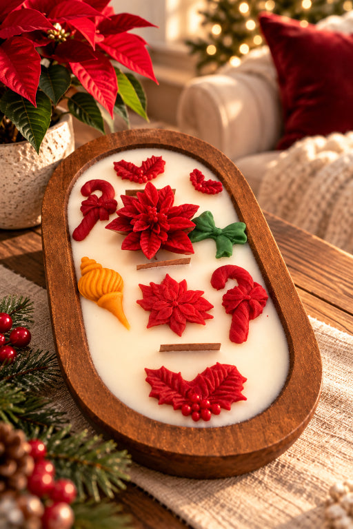 A decorative oval wood dough bowl  filled with white wax and decorated with red poinsettia and holly motifs, green leaves, candy canes, and small orange accents, styled on a table with holiday greenery and a cozy indoor background.