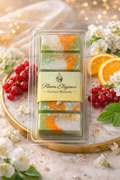 Luxury currant blossom wax melt bar with marbled green, white, and orange soy wax, finished with mica and subtle gold glitter, floating on a white background in clear clamshell packaging. 
