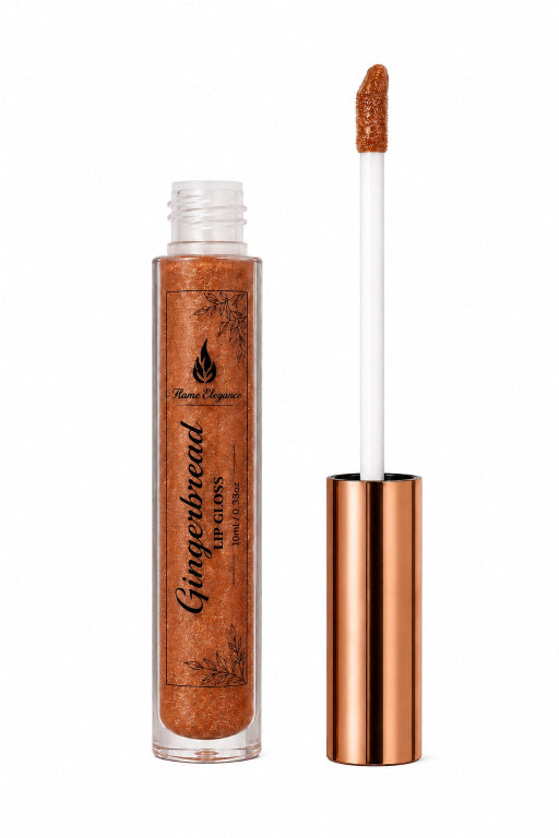 A clear tube of lip gloss with a metallic rose-gold cap, shown next to its applicator wand. The gloss inside is a shimmering gingerbread brown, and the label reads 'Gingerbread lip gloss' by 'Flame Elegance"