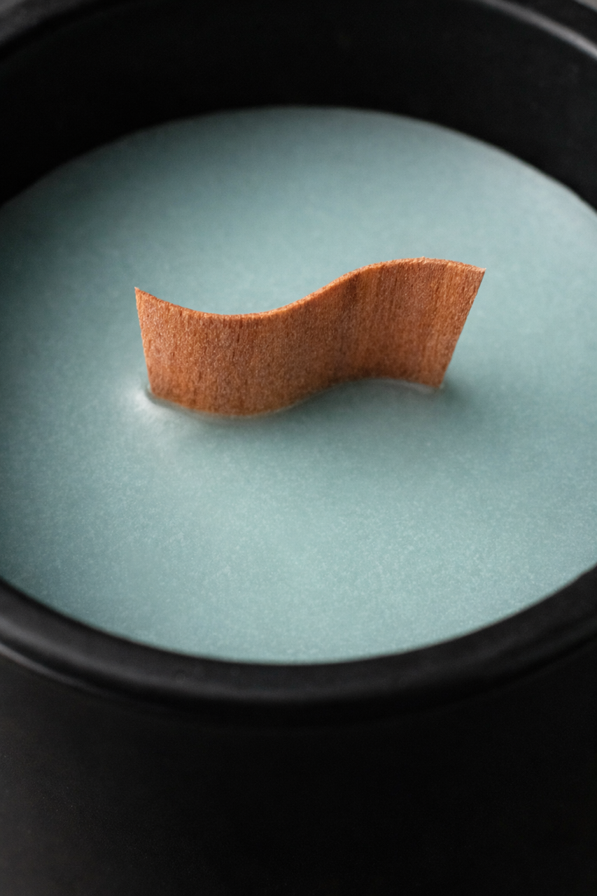 Jasmine sea flower aromatherapy candle with soft flora and ocean air notes, clean burn soy wax, wood wick, and elegant black ceramic vessel with lid. 