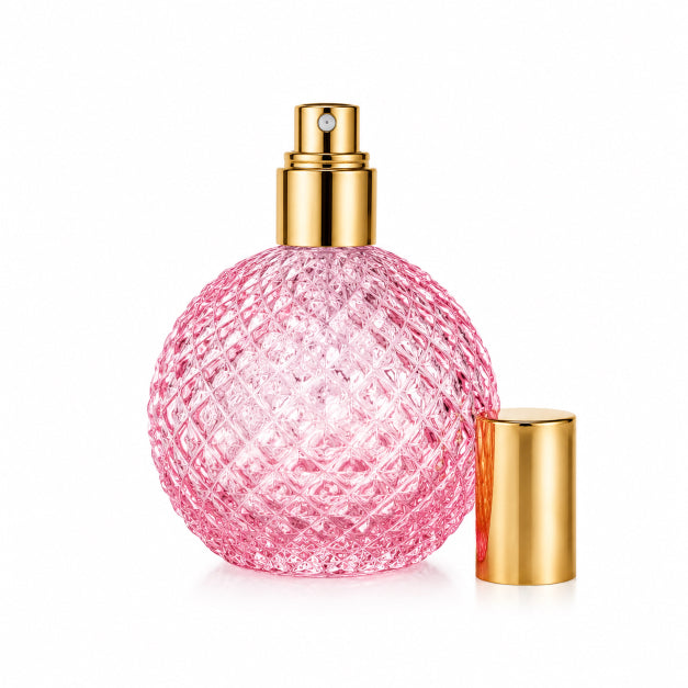 A pink textured glass perfume bottle with a gold spray nozzle and a separate gold cap, shown on a clean white background. Love Spell by Flame Elegance.
