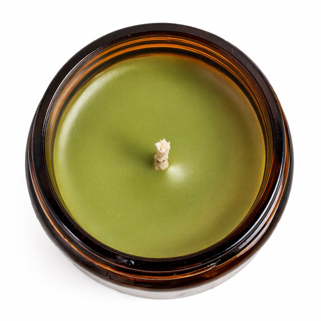 Green candle in a brown jar on a white background by flame elegance