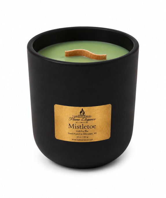 A black ceramic jar candle with a light green wax fill, a wooden wick, and a gold label reading Flame Elegance  Mistletoe scented wax'.