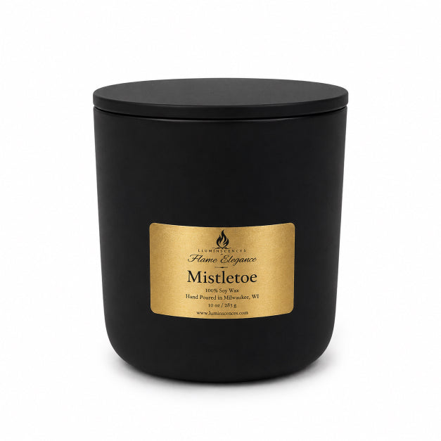 A matte black jar candle with a matching black lid and a rectangular gold label reading 'Flame Elegance Mistletoe' on a clean white background.