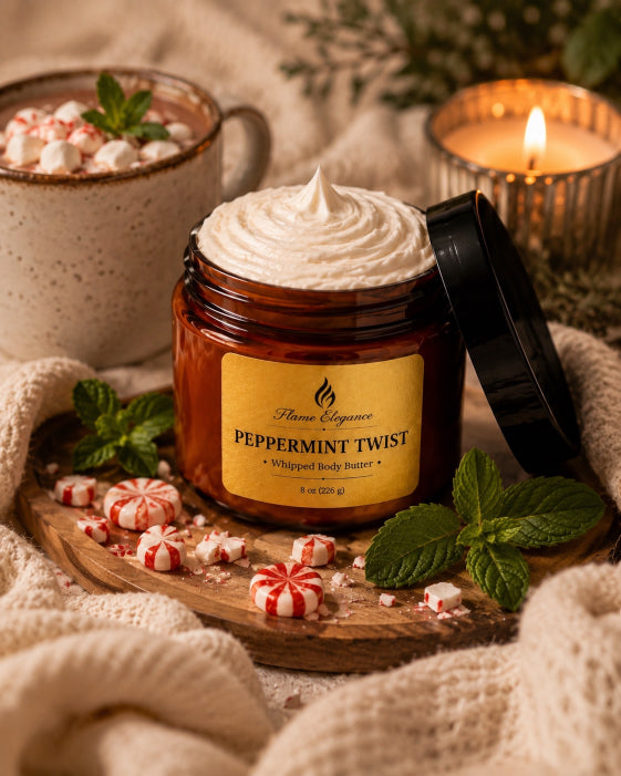 A jar of Flame Elegance Peppermint Twist whipped body butter sits open on a wooden board with its lid leaning beside it. The amber jar is filled with thick white whipped balm and has a yellow label.
