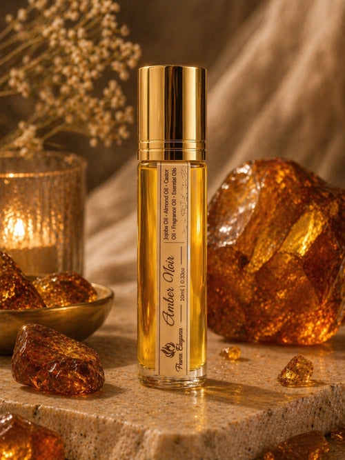 Gold bottle of Amber Oil with amber stones and a candle on a stone surface