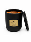 pumpkin spice soy aromatherapy candle with black vessel orange candle wood wick and lid propped up on the side. White background by Flame Elegance.