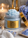 sapphire desire luxury sugar scrub by Flame Elegance blue sugar scrub with lid open and candle in background with blue flowers and blue sapphires
