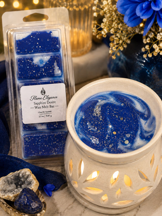 Flame Elegance Sapphire Denim wax melts shown in a clear plastic package next to a white ceramic scented candle holder filled with blue and white marbled wax and gold glitter.