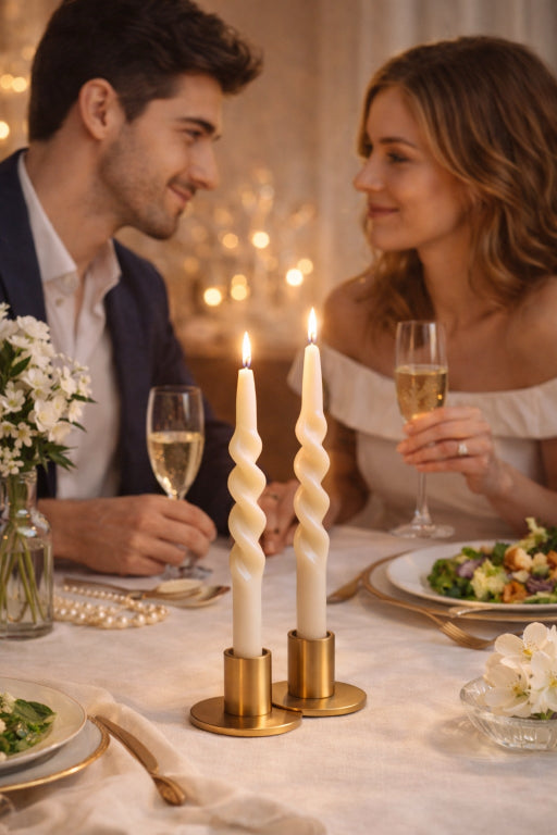 Couple enjoying champagne with a pair of Flame Elegance unscented spiral taper candles that are lit. 
