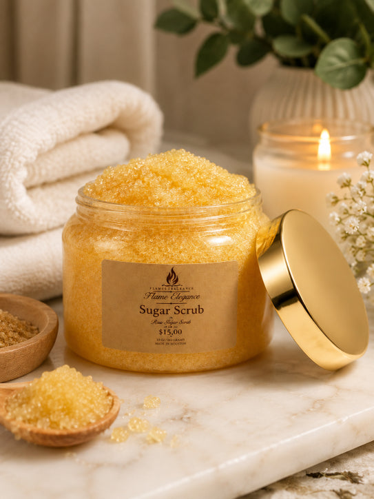 Jar of luxury gold sugar scrub with a gold lid on a marble surface, surrounded by towels and a candle scented with Rose Mist fragrance by Flame Elegance