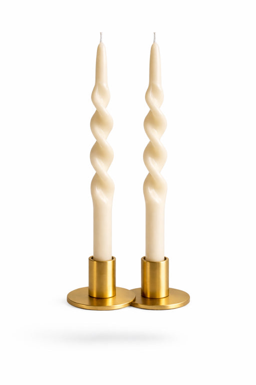 Pair of elegant ivory unscented taper candles in brass holders with white background. By Flame Elegance