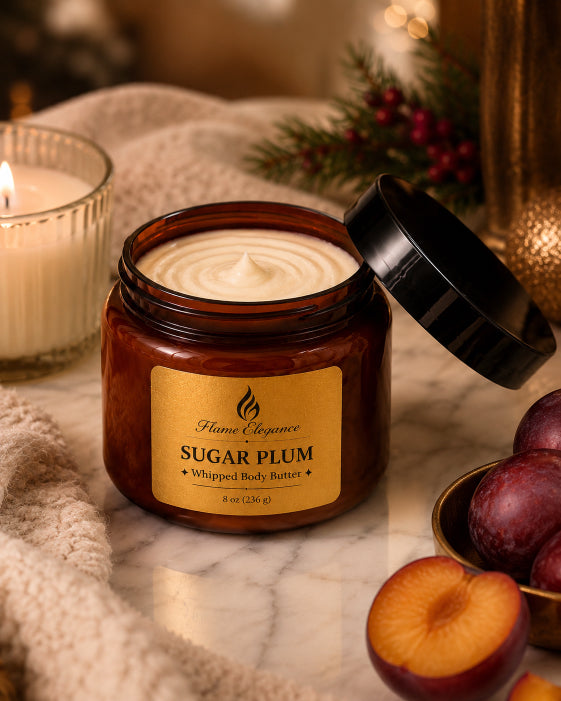 Jar of 'Sugar Plum' whipped body butter with a candle and plums on a marble surface by Flame Elegance